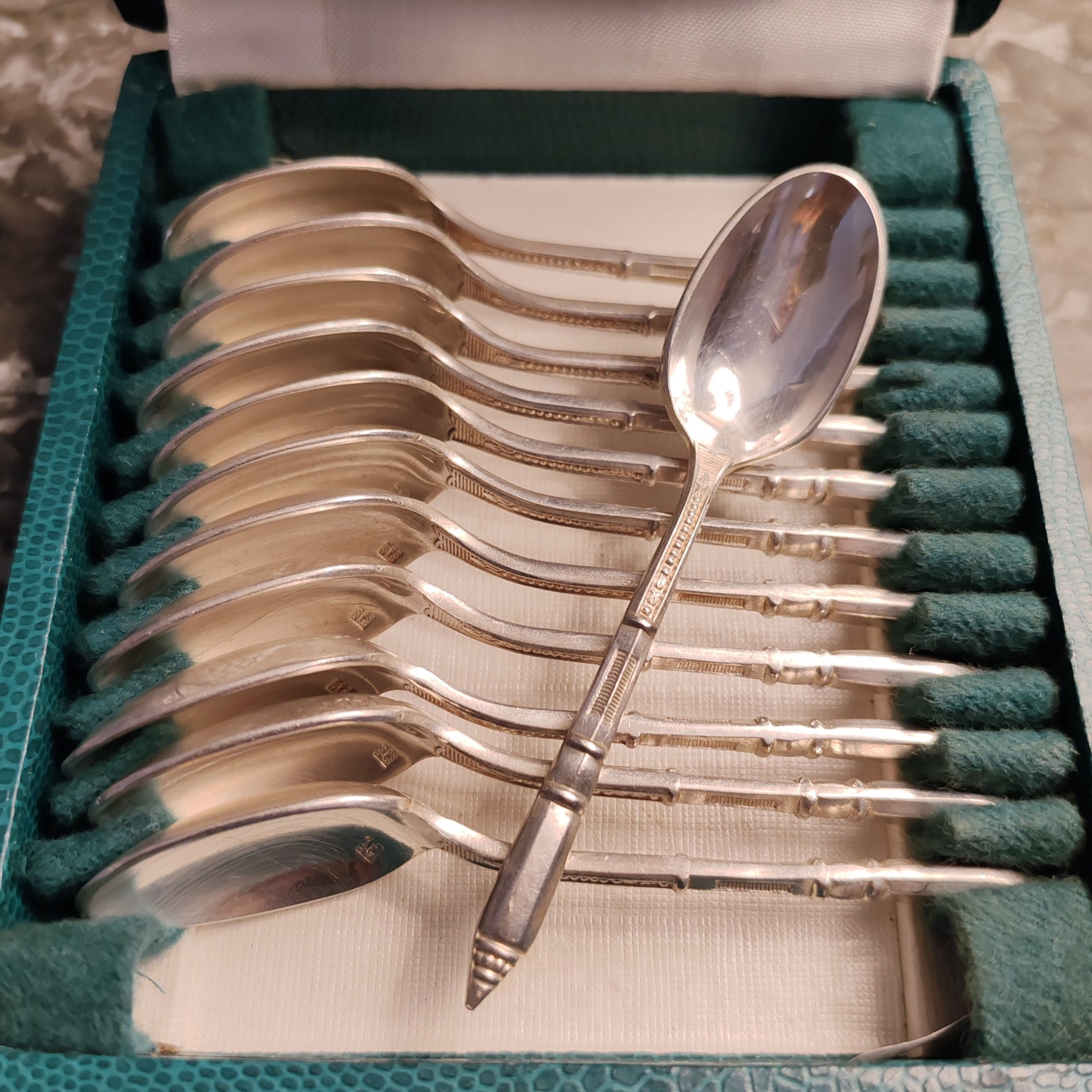 Coffret de 12 cuillères à moka ou espresso en métal argenté de la maison ERCUIS, modèle de style Art Déco au manche « à la russe » ciselé.